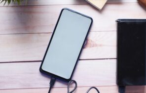 木製のデスクでモバイルバッテリーからスマートフォンを充電しているイメージ