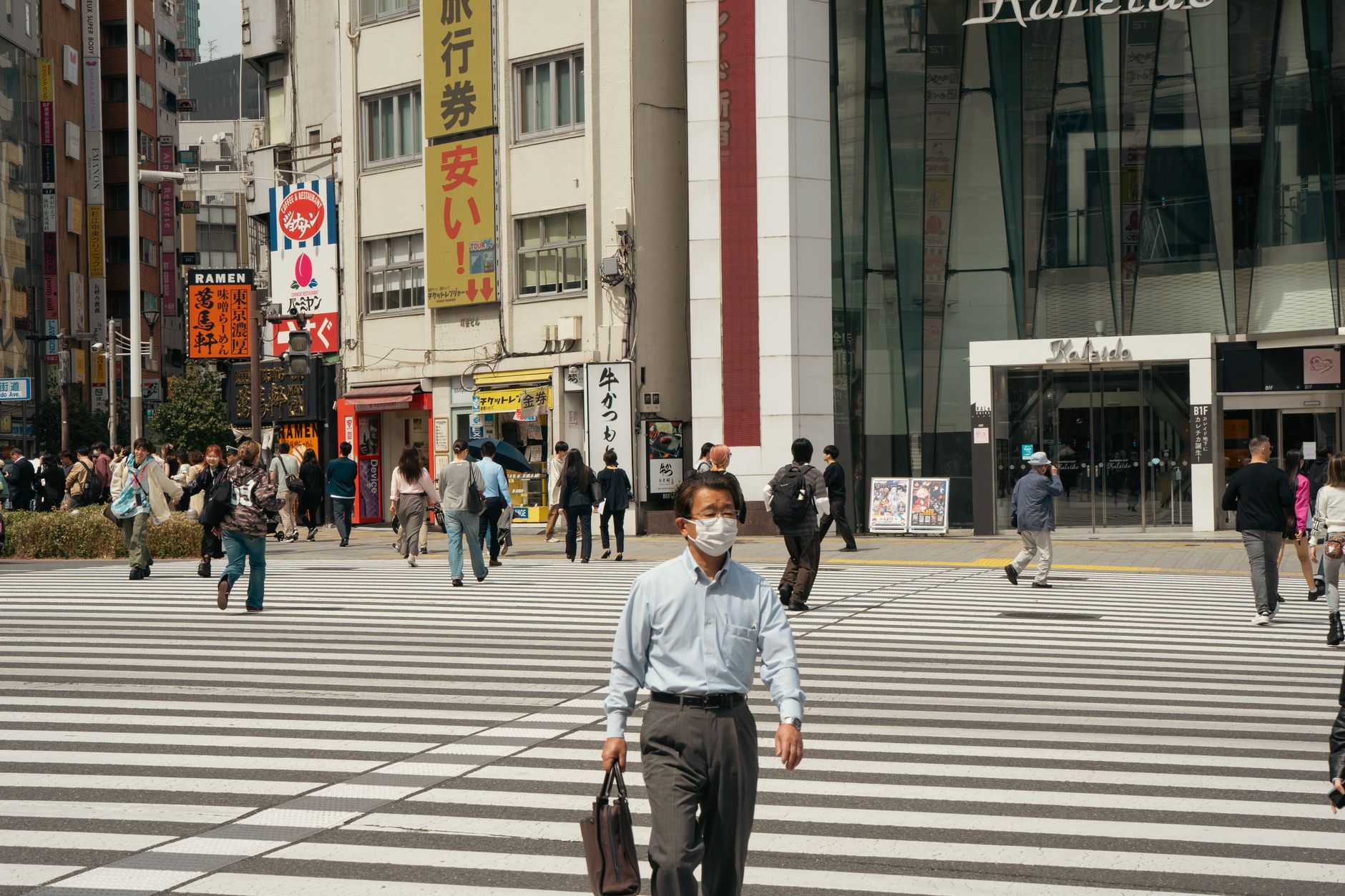 街の横断歩道を歩いて通勤する人たちのイメージ