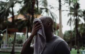 夏の屋外でタオルで汗をぬぐう人のイメージ