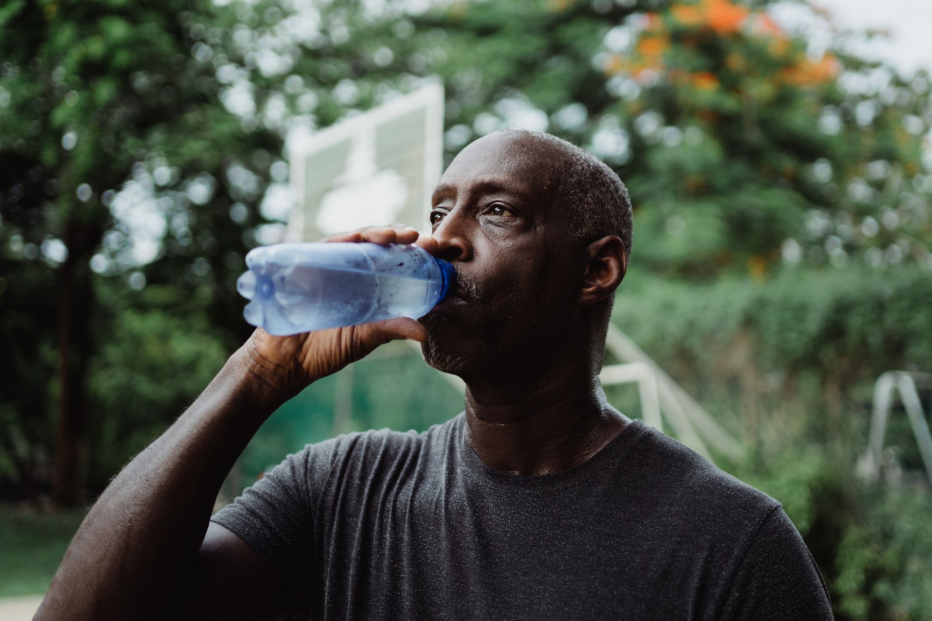 屋外でボトルの水を飲んで水分補給する人のイメージ