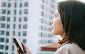 屋外でスマートフォンを操作しながらイヤホンで音楽を聴く人のイメージ