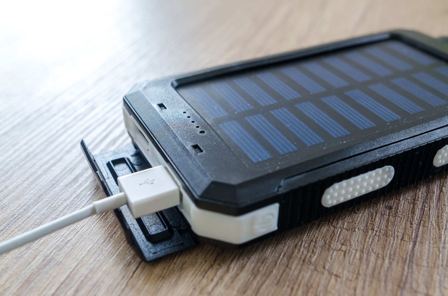 USB出力の付いたソーラーチャージャーを木のテーブルに置いたイメージ