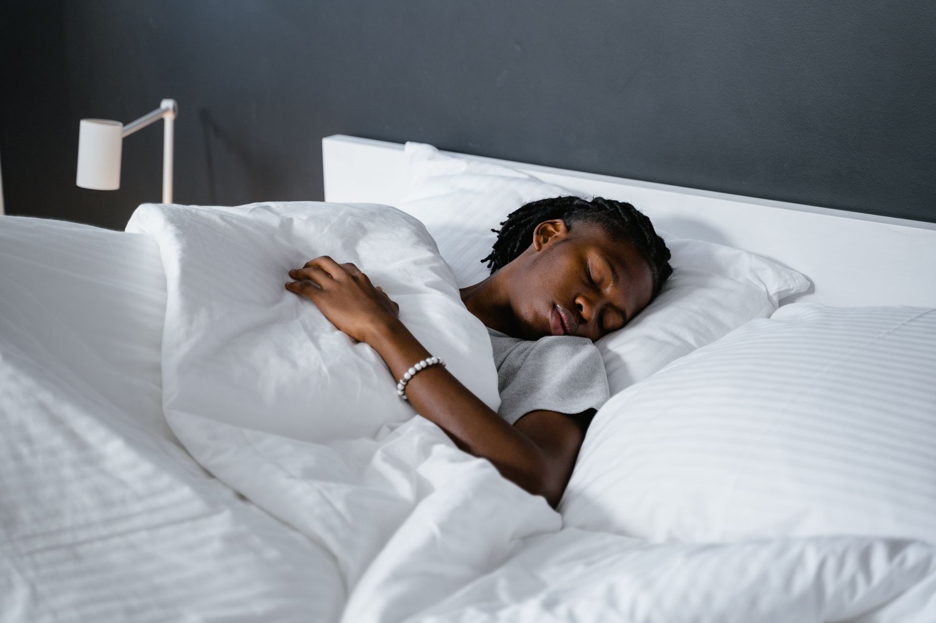 白い布団をかけてベッドで眠っている人のイメージ