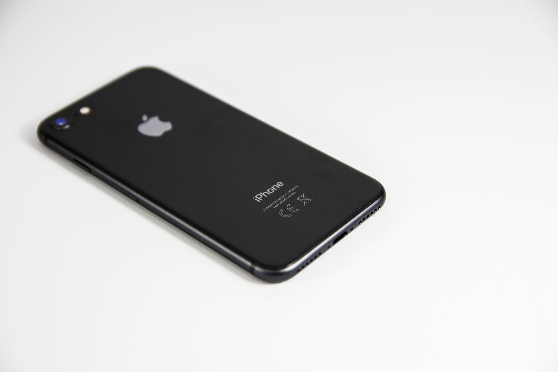 白い机の上に置いた黒いスマートフォンのイメージ