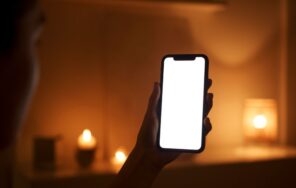 キャンドルの灯る夜の部屋でスマートフォンを手にするイメージ