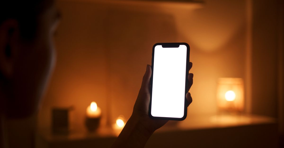 キャンドルの灯る夜の部屋でスマートフォンを手にするイメージ